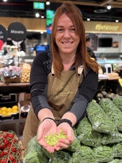 Local vendor holding lágrima peas at a market in San Sebastian